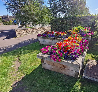 Multi level stone raised planters filled with a variety of colourful summer flowers