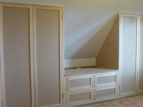 Custom built white storage units and shelving installed in a converted loft space