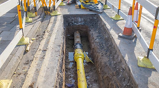 Excavated trench showing a yellow water mains pipe undergoing repair and maintenance