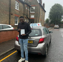 Young man standing by a silver car holding his driving pass certificate
