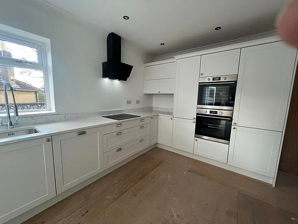 Elegant light grey bespoke kitchen in York with white marble countertops and a built in double oven