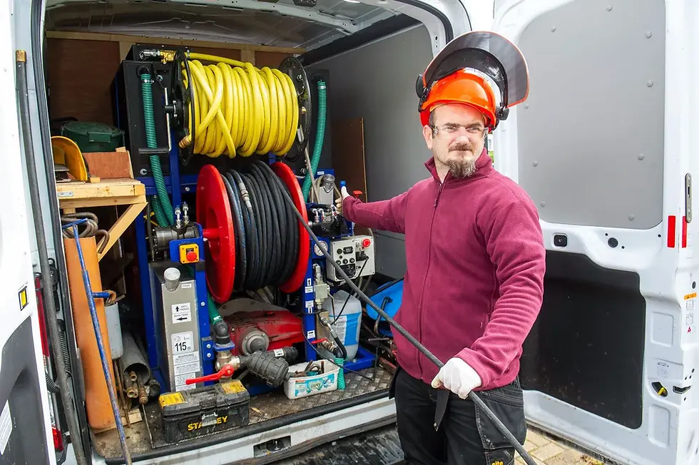 Drainage engineer in hard hat operating high pressure water jetting equipment from the back of a van