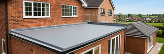 Modern flat grey rubber GRP fiberglass roof installation on a brick home extension