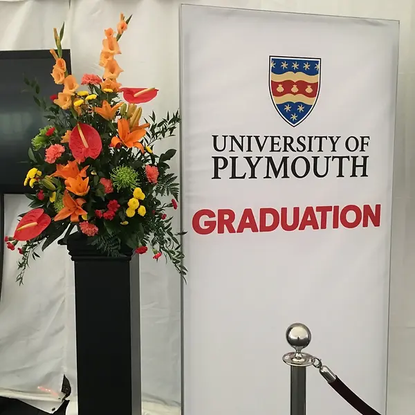Large corporate floral arrangement with orange lilies and red anthuriums at a graduation