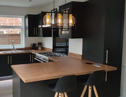 Modern L-shaped kitchen featuring dark grey cabinets wooden worktops and pendant light fixtures