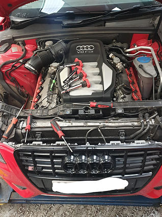 Mechanic inspecting the engine bay of a red car
