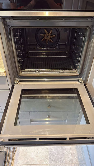 Open oven with a clean interior, front door lying flat, steel racks inside, and a circular fan at the back