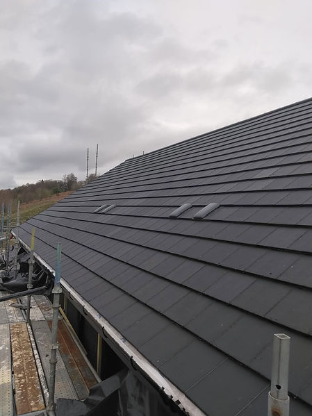 Rows of dark grey concrete roof tiles on a completed roof