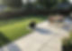 Paved garden patio with outdoor dining furniture and green lawn