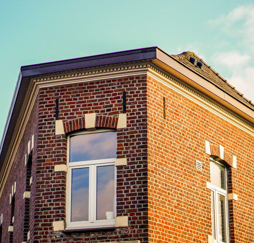 Roofline details of a traditional red brick property with stone window headers under a blue sky