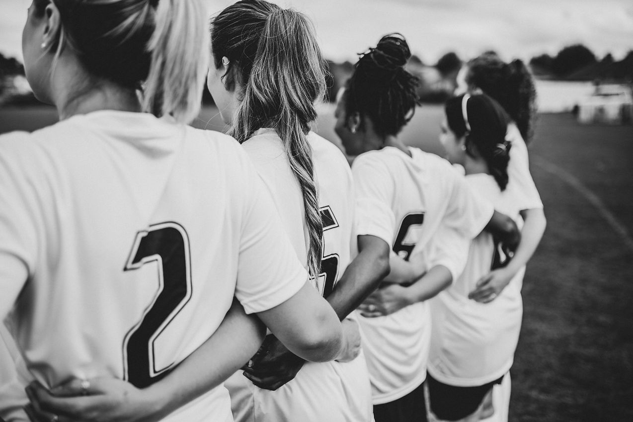 Female football players huddling together.jpg