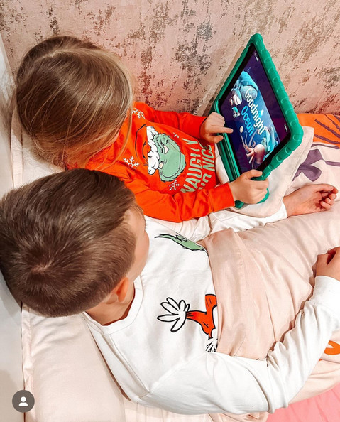 Brother and sister at bedtime story co app in bed