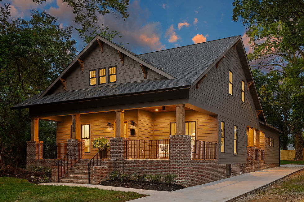 Brown wooden house with brick porch, lit warm lights, under a sunset sky. Trees surround the setting, creating a serene mood.