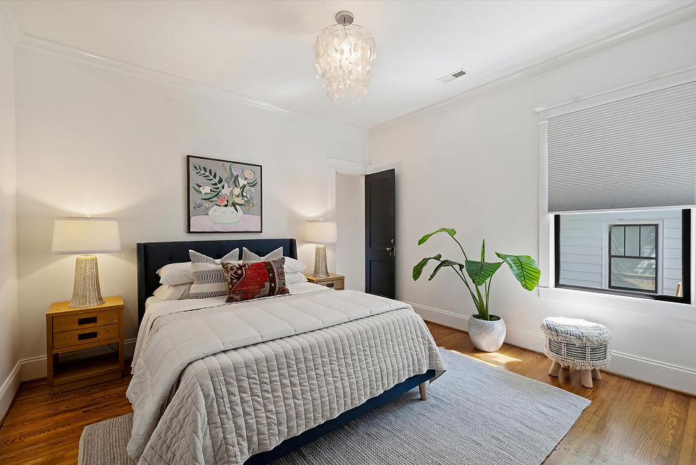 Bright modern bedroom with a neatly made bed, bedside lamps, plant, art, and window blinds; calm, airy feel