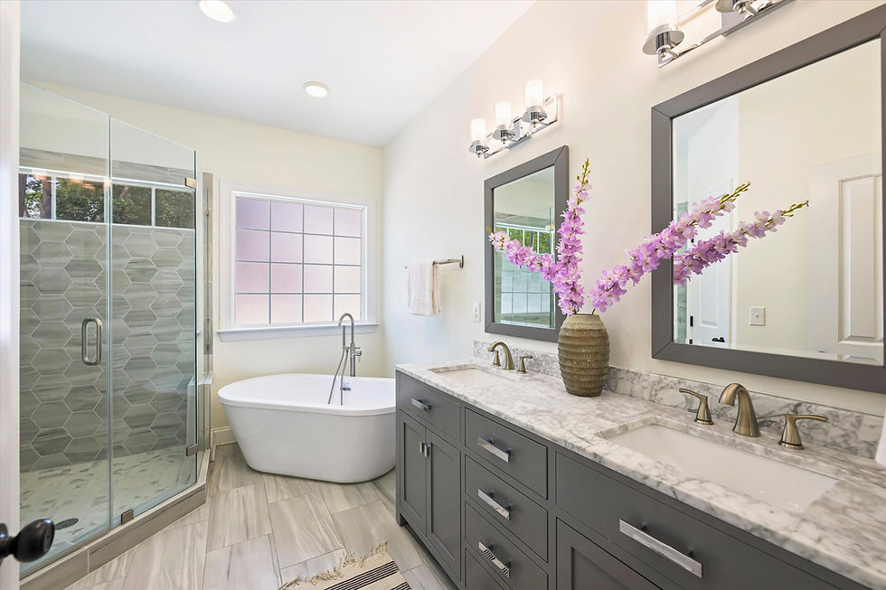 Luxurious bathroom with a glass shower, freestanding tub, dual-sink vanity, purple flowers in a vase, and soft lighting. Calm and elegant.