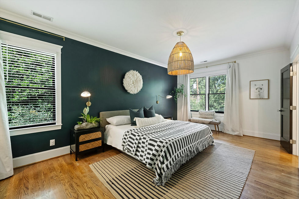 Stylish bedroom with dark green accent wall, black-and-white bedding, woven pendant light, large windows, and framed llama art.