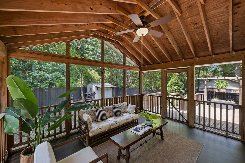 Wooden sunroom with beige sofa, striped pillows, and banana plant. Overlooks grassy backyard. Breezy, peaceful ambiance.