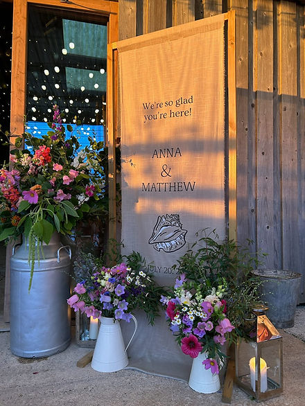 Fabric linen welcome sign for a coastal wedding in Devon with painted seashell design