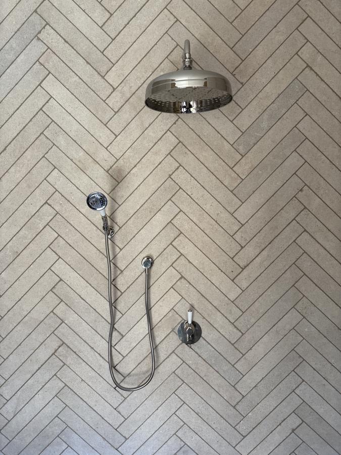 Heritage-style shower with rain head and hand shower on herringbone tile