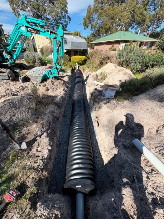Large corrugated drainage pipe laid in a trench with an excavator