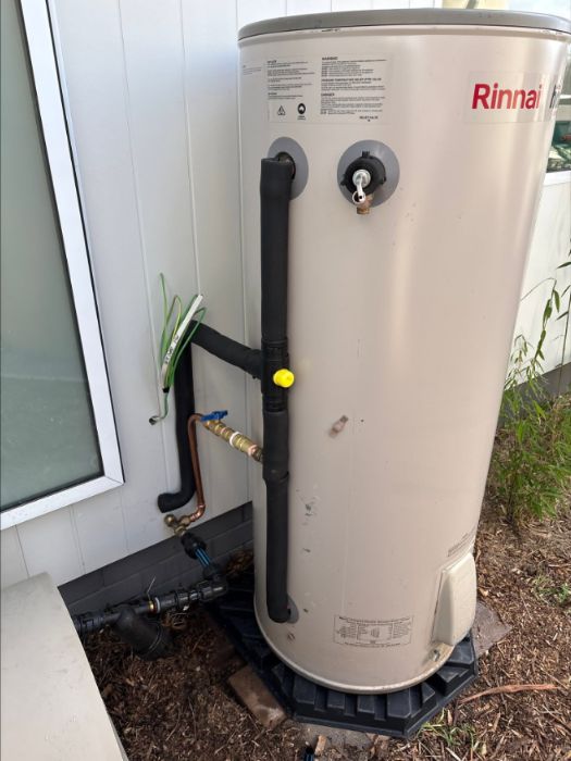 New Rinnai hot water system on a stand beside a house