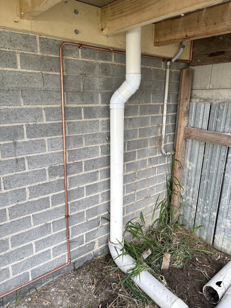 New copper water line and stormwater downpipe under a deck