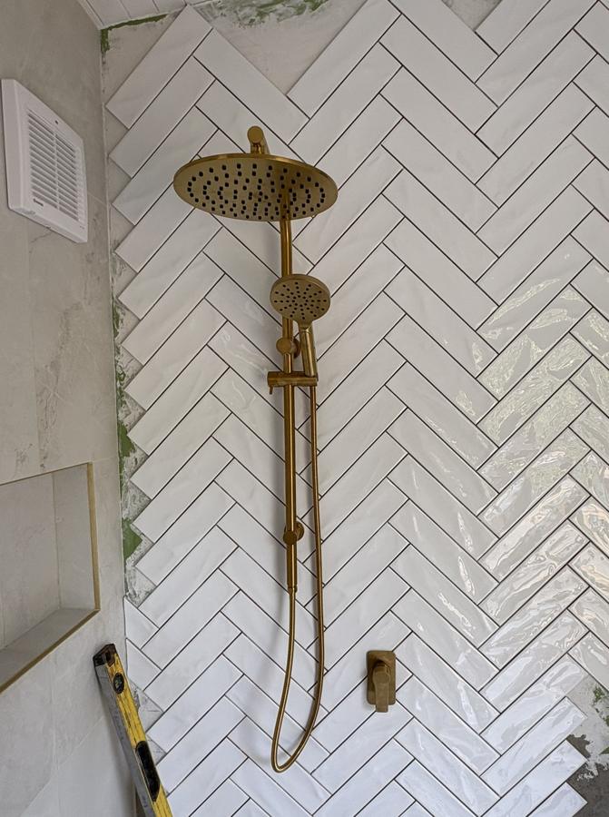 Brushed brass twin shower and mixer on herringbone tile