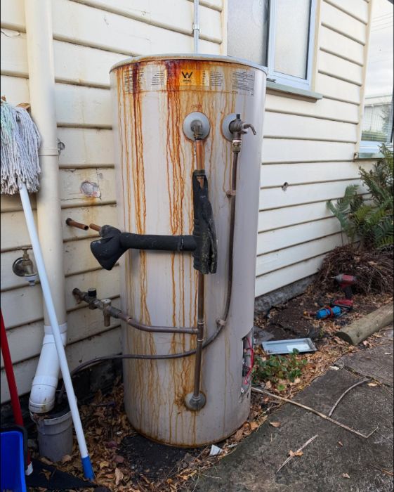 Old, rust-stained hot water system before replacement