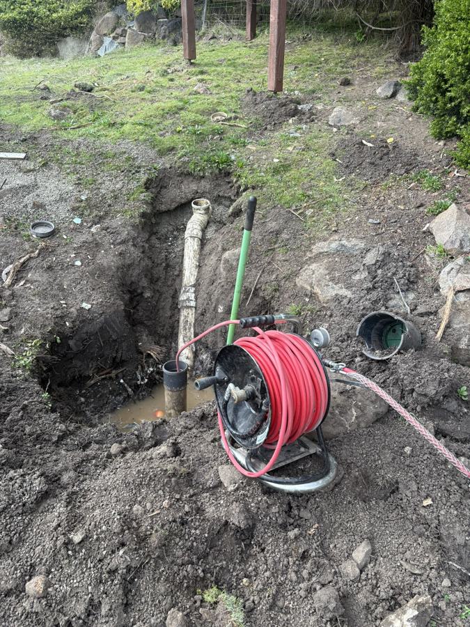 Drain jetter hose feeding into a dug-out sewer line