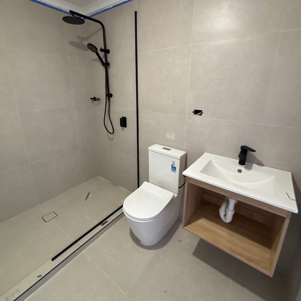 Renovated bathroom with matte black shower, toilet suite and wall-hung vanity