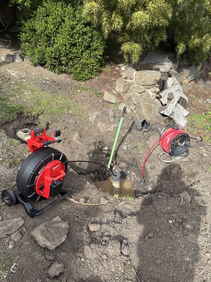 Drain inspection camera fed into a drain riser in a backyard