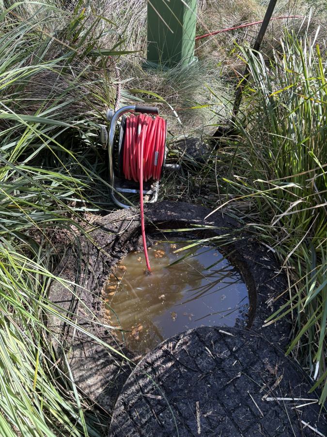 Before: Pit full of backed-up water, with the jetter hose going in.