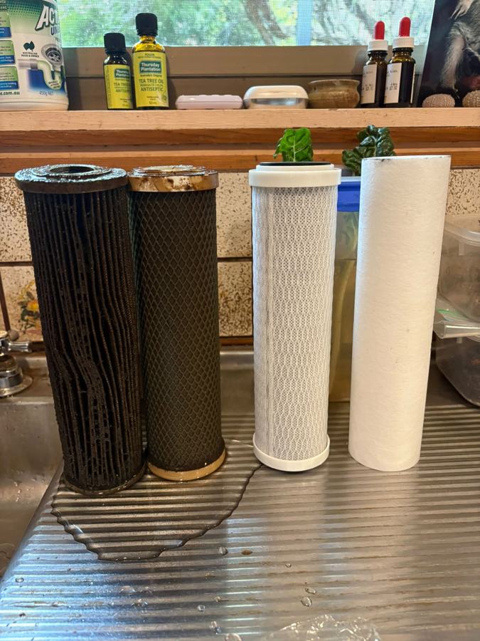 Two used water filters beside two new replacement filters