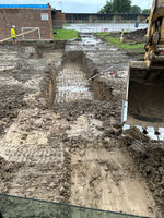 Excavator moving soil and debris on a construction site, preparing the ground for foundation work.