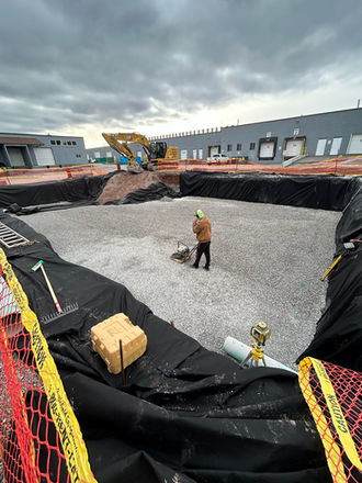 Excavator leveling the site with gravel spread evenly across the construction area.