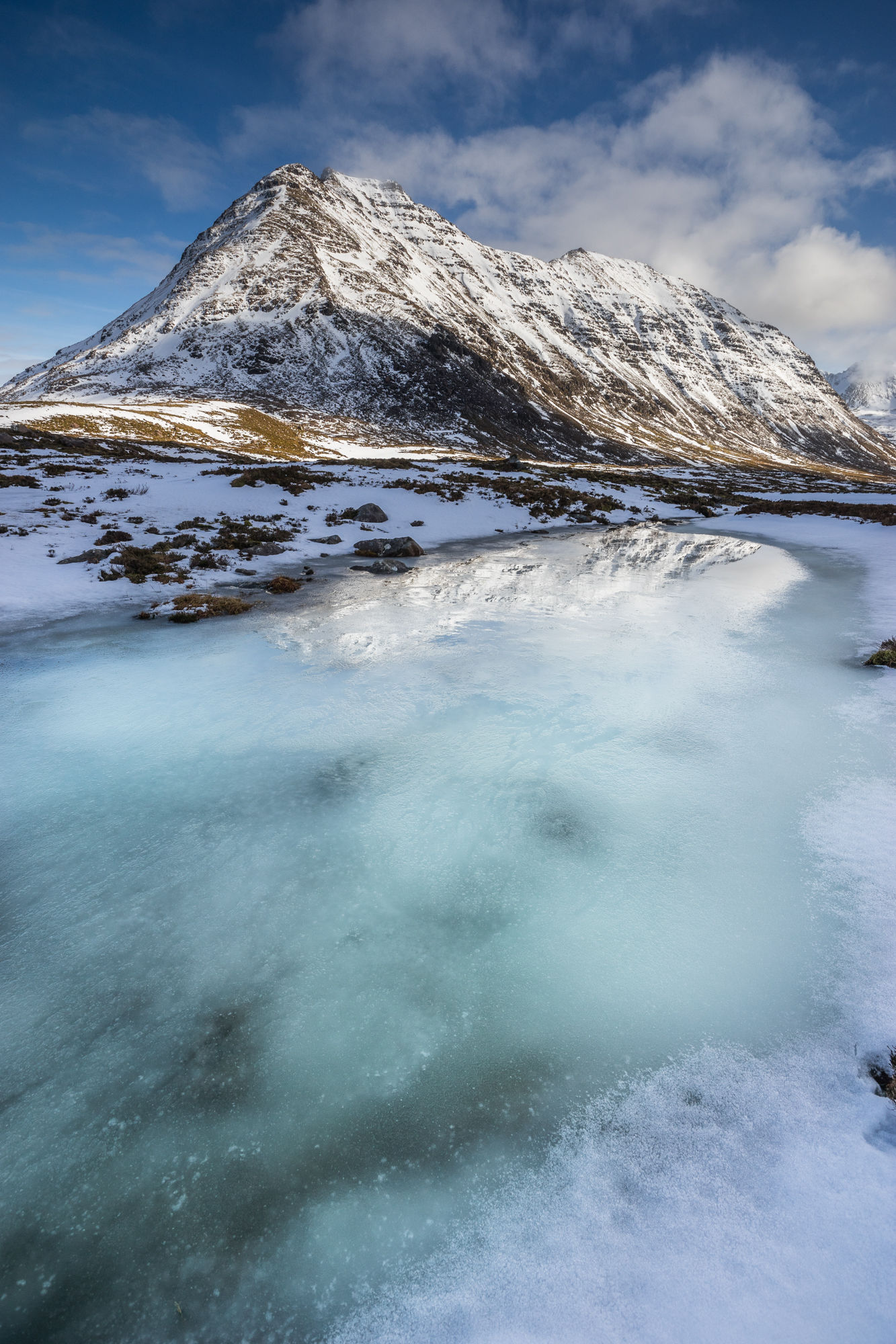 Frozen burn with aqua ice leading towards Beinn Dearg. Torridon.