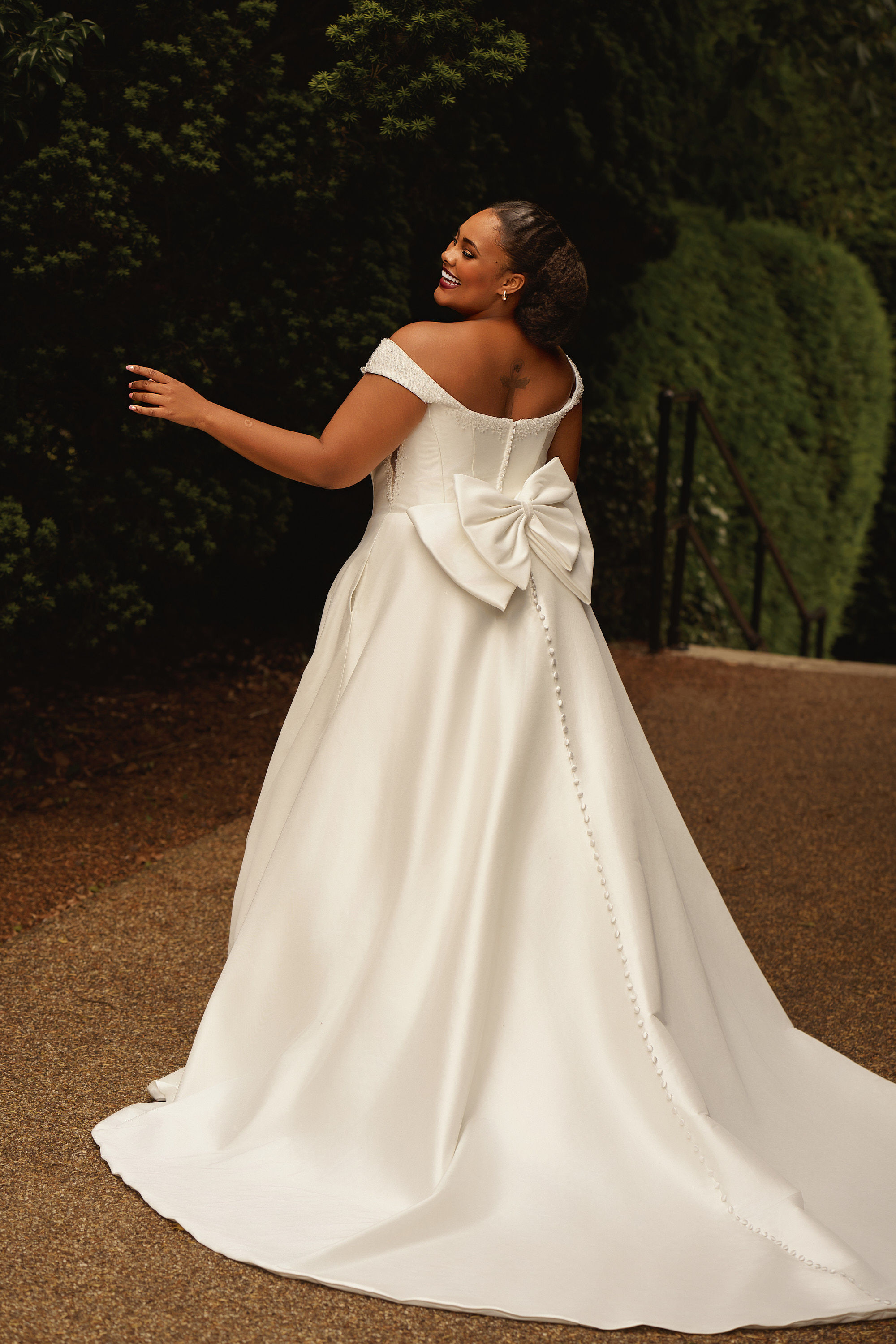 Back view of Envy by Phoenix PH8265 plus-size satin A-line wedding dress with bow detail and off shoulder straps