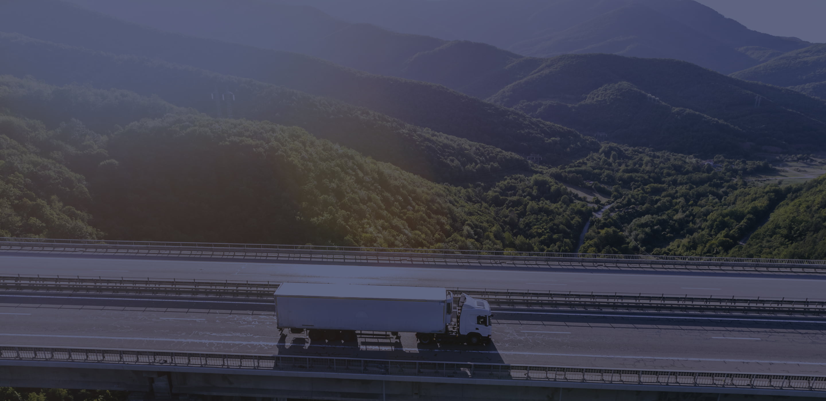Camiones en autopista con montañas al atardecer