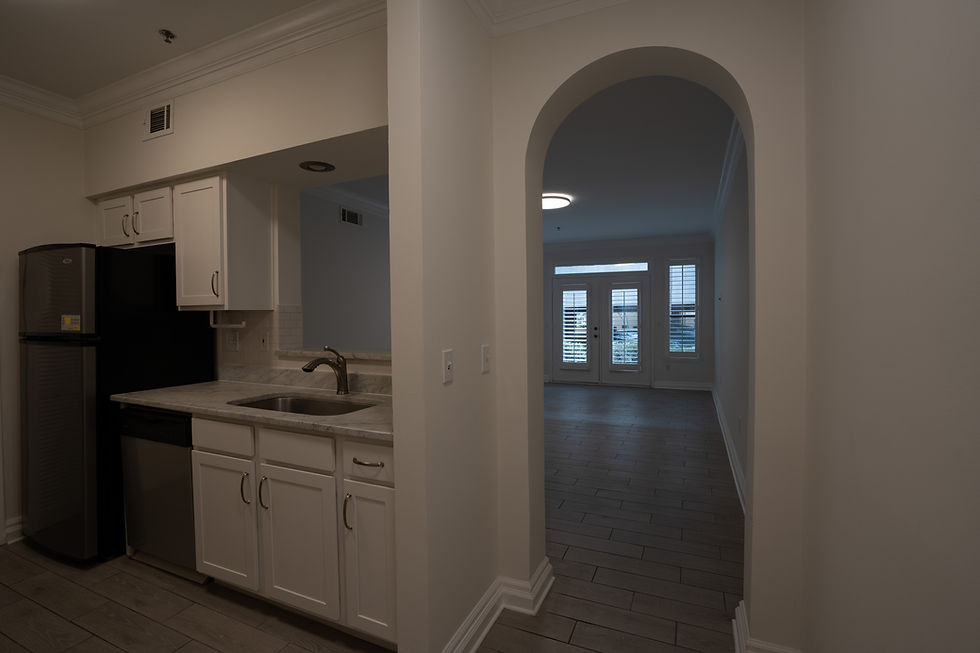 Modern kitchen with white cabinets next to an arched doorway.