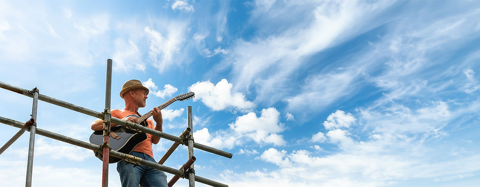 Nick Peers holding a guitar on a scaffold