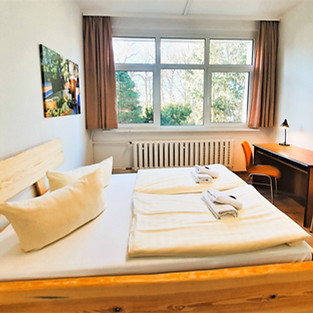 Doppelzimmer Gästehaus_Fenster_Bett_Tisch.JPG