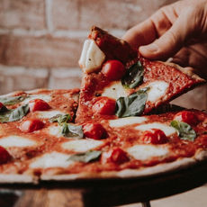 Someone grabbing a piece of pizza