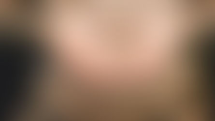 Hands form a heart shape over a pregnant belly, wearing a beige sweater. Soft lighting creates a warm, serene mood.