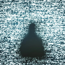Silhouette of a person in a dress seen through sparkling water. The scene has a mysterious, tranquil mood with bright reflections.