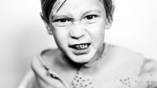 black and white image if a little kid making a screwy face at the camera