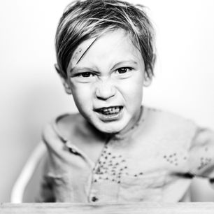 black and white image if a little kid making a screwy face at the camera