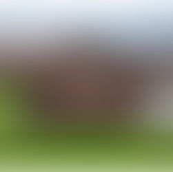 Brick church with a large cross and a brown roof. Overcast sky in the background; sign reads Beacon International Centre. Green grass surrounds.