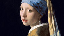 Portrait of a young woman in a blue headscarf and pearl earring, looking over her shoulder against a dark background. Girl with a Pearl Earring painting.