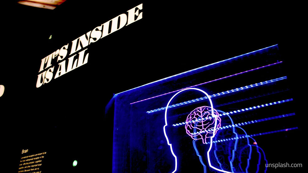 Neon outlines of human heads with brains against a black background. White text reads "IT'S INSIDE US ALL." Vibrant and thought-provoking.