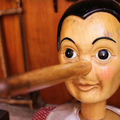 Wooden puppet with a long nose, seated in a warmly lit workshop. The background features wooden tools, creating a whimsical feel.